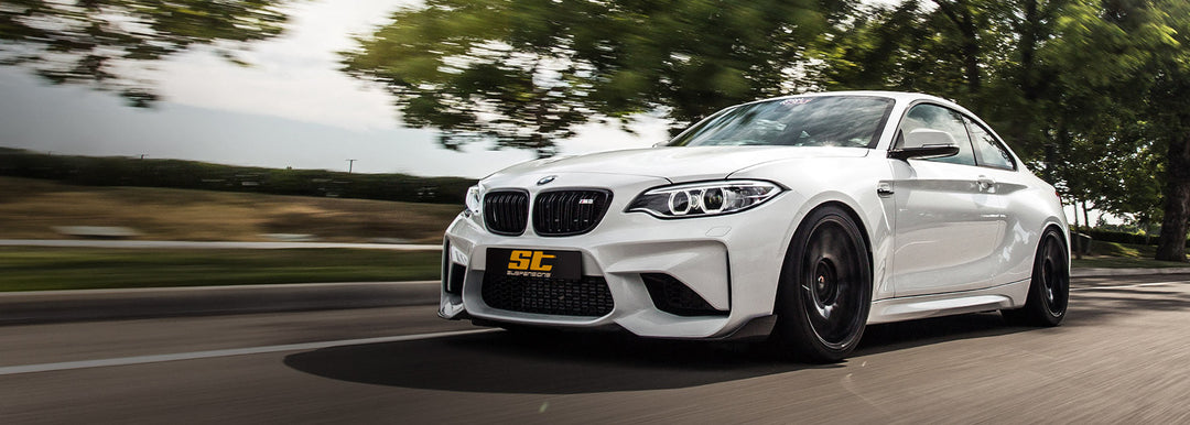 White BMW M2 lowered on ST XTA coilovers driving on a road